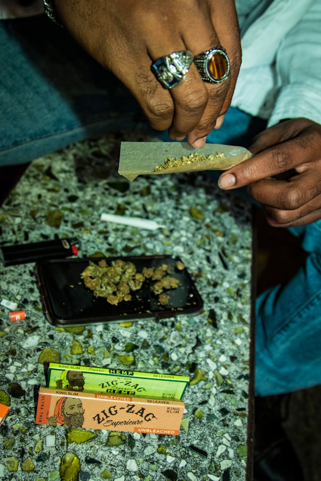 Hand sprinkles Weed into joint (photo by LexScope)